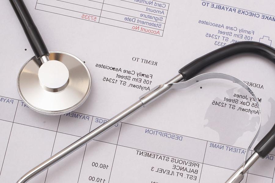 A paper billing statement with a stethoscope laid on top